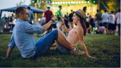 man and woman sitting on the grass outside sharing a drink
