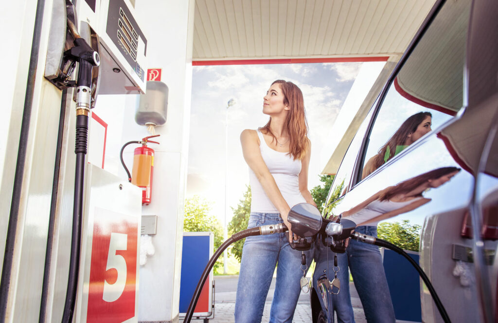 woman fueling her car pumping gas in warm sunny weather