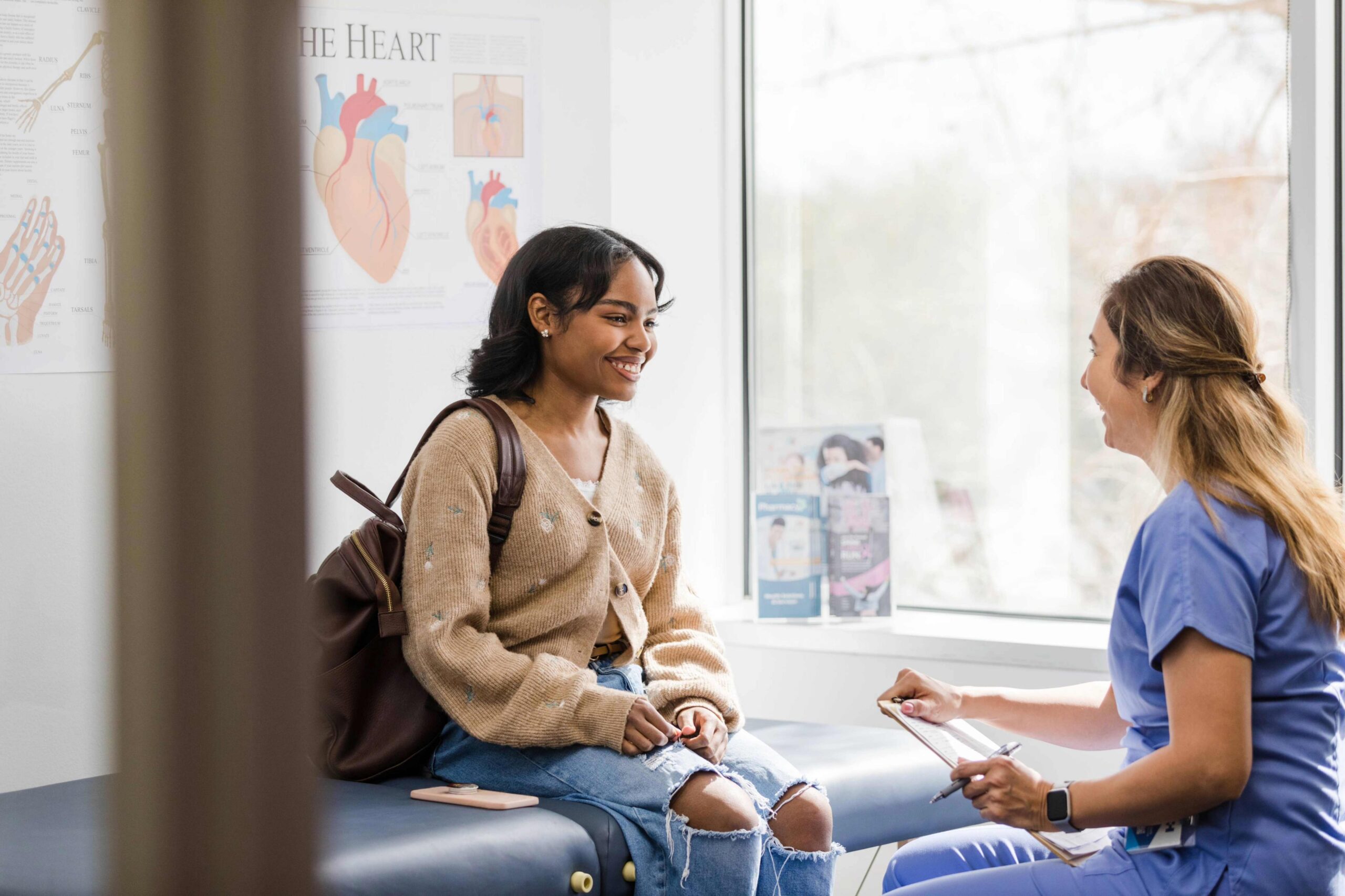 Smiling young woman talking with a nurse during a visit at a bright medical office